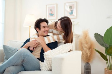 Genç bir çift kanepede dinleniyor. Parlak bir oturma odasında bitkilerle keyifli bir anı paylaşıyorlar..