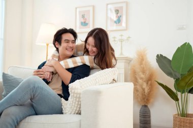 Genç bir çift kanepede dinleniyor. Parlak bir oturma odasında bitkilerle keyifli bir anı paylaşıyorlar..