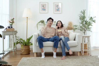 İki kişi, şık bir oturma odasında rahat bir kanepede otururken aynı kahkahayı paylaşıyor..