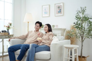 İki kişi, şık bir oturma odasında rahat bir kanepede otururken aynı kahkahayı paylaşıyor..