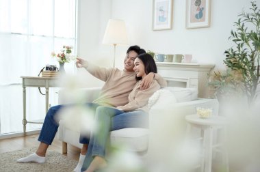 İki kişi, şık bir oturma odasında rahat bir kanepede otururken aynı kahkahayı paylaşıyor..