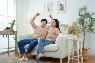 İki kişi, şık bir oturma odasında rahat bir kanepede otururken aynı kahkahayı paylaşıyor..