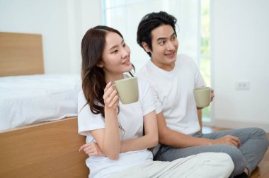 Sabah ışığıyla dolu bir yatak odasında iki kişi kahkaha atıp kahve yudumluyor..