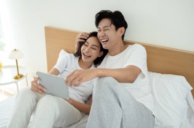 İki insan güler ve sabah güneşinde tablet kullanırken rahat bir anı paylaşır..