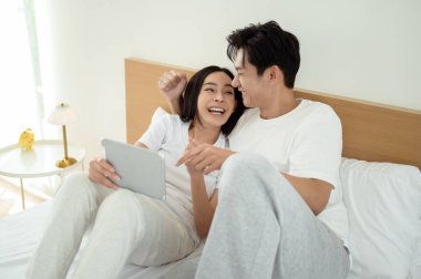 İki insan güler ve sabah güneşinde tablet kullanırken rahat bir anı paylaşır..