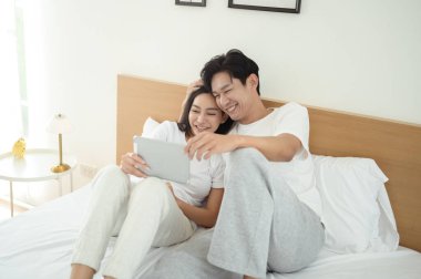 İki insan güler ve sabah güneşinde tablet kullanırken rahat bir anı paylaşır..