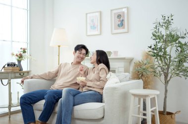 İki kişi, şık bir oturma odasında rahat bir kanepede otururken aynı kahkahayı paylaşıyor..