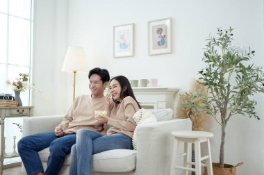 İki kişi, şık bir oturma odasında rahat bir kanepede otururken aynı kahkahayı paylaşıyor..