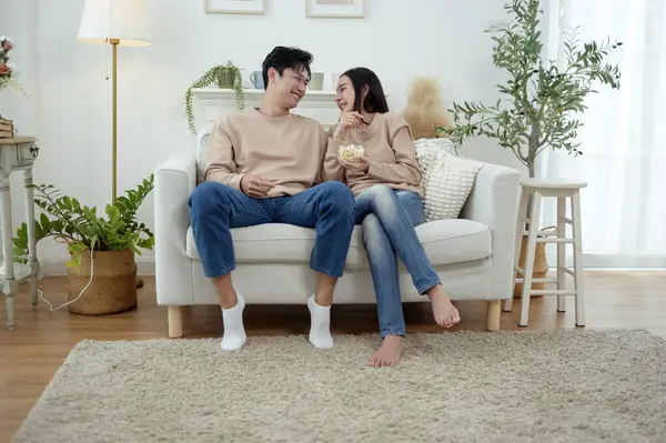 İki kişi, şık bir oturma odasında rahat bir kanepede otururken aynı kahkahayı paylaşıyor..