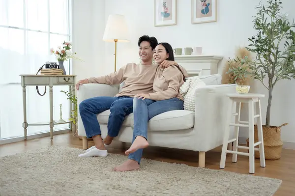 İki kişi, şık bir oturma odasında rahat bir kanepede otururken aynı kahkahayı paylaşıyor..