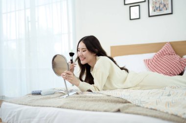 Genç Asyalı kadın evde makyaj yapıyor.