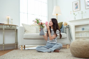 Asyalı gülümseyen kadın kavanoza güzel çiçekler koyuyor