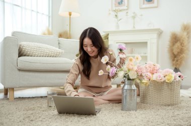 Asyalı gülümseyen kadın kavanoza güzel çiçekler koyuyor