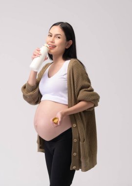 Beyaz arka plan stüdyosundan süt içen hamile kadın.