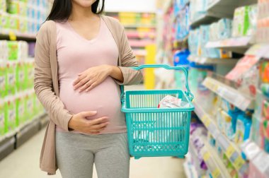 Güzel hamile bir kadın alışveriş merkezinde yeni doğan ürünleri alıp bebek için hazırlanıyor..