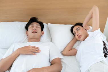 Kadın rahat bir yatak odasında onun yanında uyumaya çalışırken erkek horluyor..