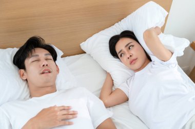 Kadın rahat bir yatak odasında onun yanında uyumaya çalışırken erkek horluyor..