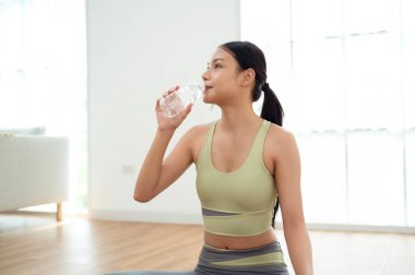 Yoga egzersizinden sonra su içen genç Asyalı kadın.