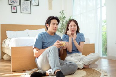 Genç bir çift, sıcak yatak odalarının zemininde dinlenirken patlamış mısır paylaşır ve gülümser..