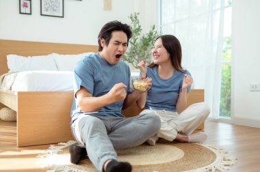 Genç bir çift, sıcak yatak odalarının zemininde dinlenirken patlamış mısır paylaşır ve gülümser..