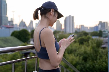 Meşgul bir şehir manzarasını görmezden gelen bir kadın akıllı telefonuyla sohbet eder..