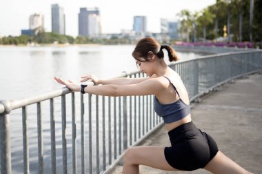 Bir kadın, şehir parkındaki bir rıhtımda esneme egzersizi yapıyor..