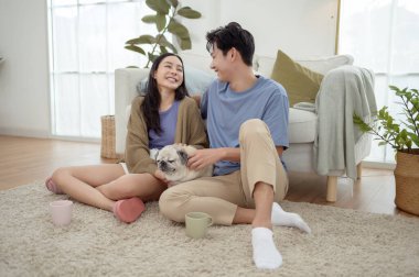 Köpekleri ile oynarlarken gülümseyen bir çift güzel ışıklandırılmış bir oturma odasında yumuşak bir halıda.