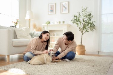 Köpekleri ile oynarlarken gülümseyen bir çift güzel ışıklandırılmış bir oturma odasında yumuşak bir halıda.