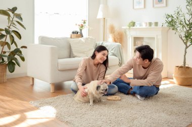 Köpekleri ile oynarlarken gülümseyen bir çift güzel ışıklandırılmış bir oturma odasında yumuşak bir halıda.