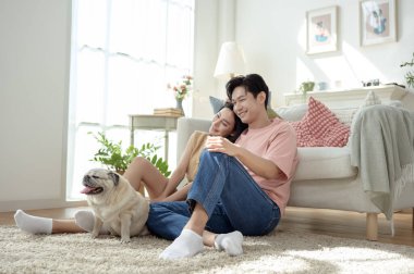 Köpekleri ile oynarlarken gülümseyen bir çift güzel ışıklandırılmış bir oturma odasında yumuşak bir halıda.