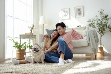 Köpekleri ile oynarlarken gülümseyen bir çift güzel ışıklandırılmış bir oturma odasında yumuşak bir halıda.