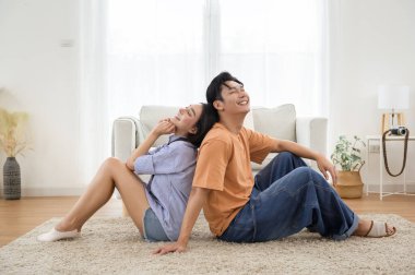 Parlak, havadar bir oturma odasında, yumuşak bir halının üzerinde sırt sırta verip rahatlayan bir çift..