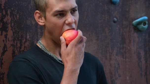 若い男がアップルを屋外で食べてる 健康的なライフスタイル 高品質のフルHd映像 — ストック動画