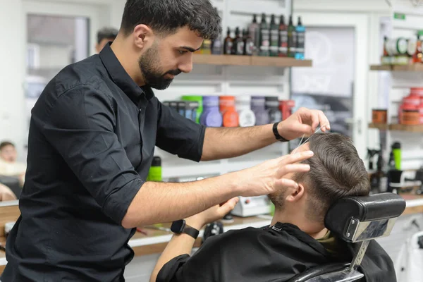 barber makes eyebrow correction for a man in the salon with a thread