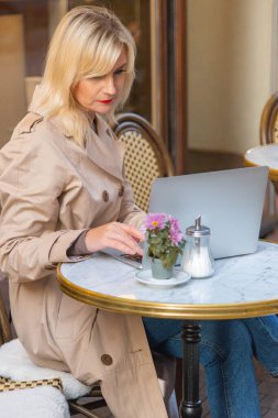 young woman businesswoman sits in a cafe behind a laptop. Business, work online. High quality photo