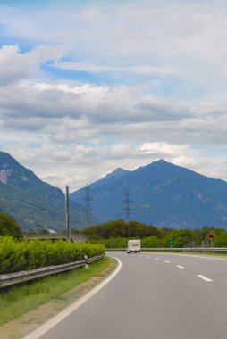 Yüksek dağ sıralarının arka planına karşı asfalt yol.