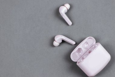 Düz depolama konsepti: kulaklıklar ve pastel renkli arka planda akıllı telefon. Pembe gri arkaplanda kablosuz kulaklıklar, üst görünüm, kopyalama alanı.