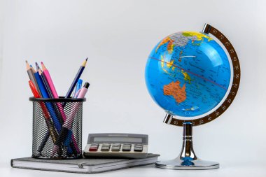 Küre, defter yığını ve kalemler. Okul çocukları ve öğrenciler için aksesuarlar. Okul konseptine geri dönelim..