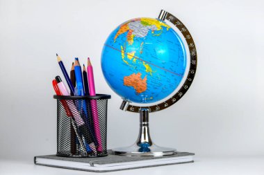 Küre, defter yığını ve kalemler. Okul çocukları ve öğrenciler için aksesuarlar. Okul konseptine geri dönelim..