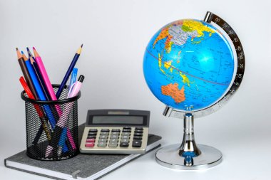 Küre, defter yığını ve kalemler. Okul çocukları ve öğrenciler için aksesuarlar. Okul konseptine geri dönelim..