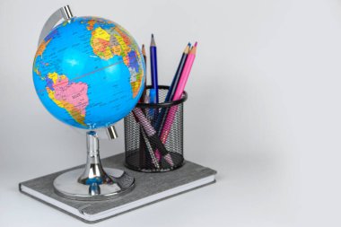 Küre, defter yığını ve kalemler. Okul çocukları ve öğrenciler için aksesuarlar. Okul konseptine geri dönelim..
