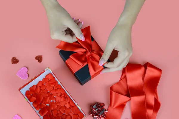 情人节的概念 女性手用红丝带包裹礼物的特写 手工制作 桌子装饰 — 图库照片