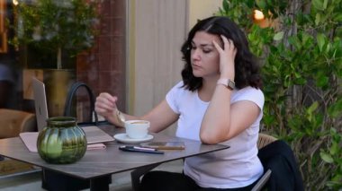 Kahve içen ve dizüstü bilgisayara bakan güzel genç bir kadın. Yüksek kaliteli FullHD görüntüler