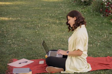 Parkta dizüstü bilgisayarla çalışan genç bir kadın. Yüksek kalite fotoğraf