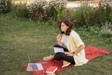 Parkta dizüstü bilgisayarla çalışan genç bir kadın. Yüksek kalite fotoğraf