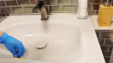 Lastik eldivenli bir elin yakın çekimi banyodaki musluğu yıkar. Yüzü olmayan. Yüksek kaliteli FullHD görüntüler