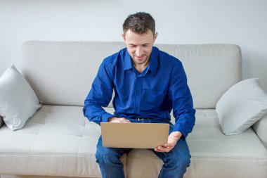 Evinden bilgisayar başında çalışan genç bir adam. Parlak, rahat bir oda, eğitim ve iş. Yüksek kalite fotoğraf