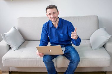 Evinden bilgisayar başında çalışan genç bir adam. Parlak, rahat bir oda, eğitim ve iş. Yüksek kalite fotoğraf