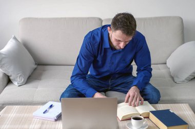 Evinden bilgisayar başında çalışan genç bir adam. Parlak, rahat bir oda, eğitim ve iş. Yüksek kalite fotoğraf