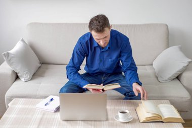 Evinden bilgisayar başında çalışan genç bir adam. Parlak, rahat bir oda, eğitim ve iş. Yüksek kalite fotoğraf